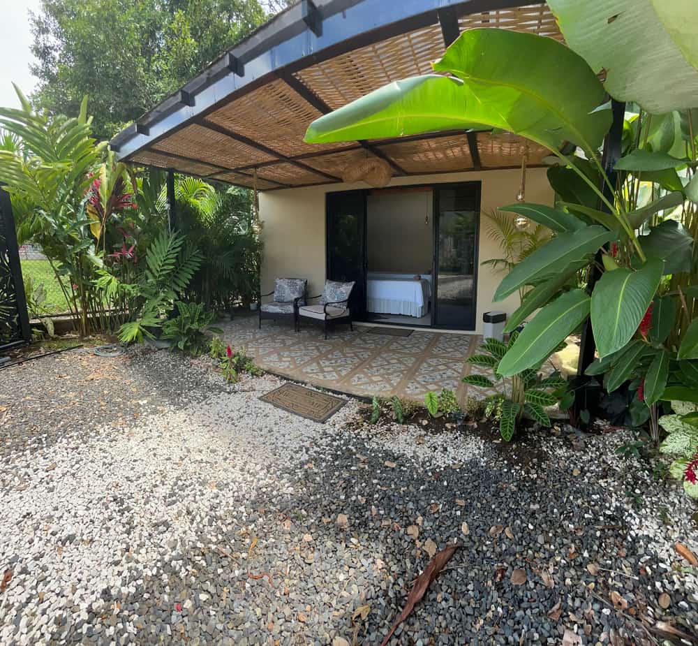 La terraza cubierta de Reborn Spa con pérgola de caña y sillones, entre hojas de platanillo
